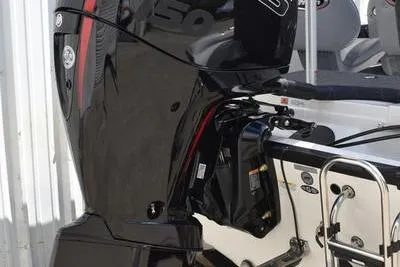 Slide: The Image of 2024 Triton 186 Allure boat with canopy, parked on a trailer beside a metal building. - 2