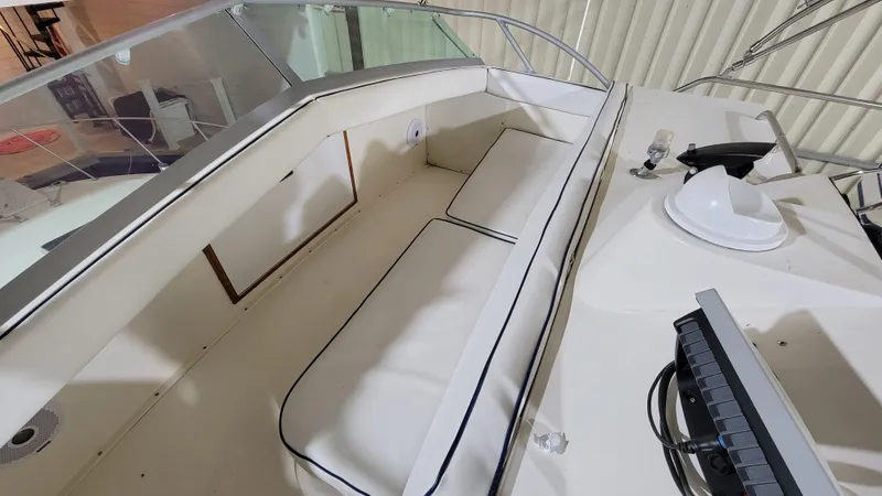 Slide: The Image of 1983 Bertram 33 Flybridge Cruiser interior with white cushioned seating and navigation equipment. - 15