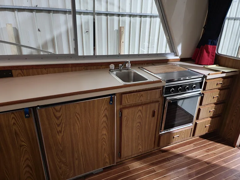 Slide: The Image of 1983 Bertram 33 Flybridge Cruiser kitchen with wood cabinets, sink, and stove. - 2