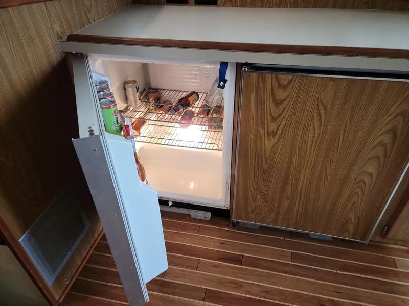 Slide: The Image of Open fridge in 1983 Bertram 33 Flybridge Cruiser, wooden interior, stocked with drinks and snacks. - 21