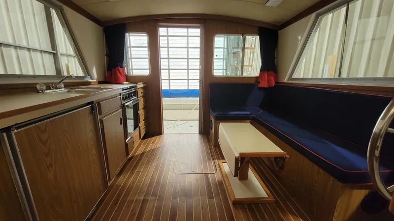 Slide: The Image of Interior of 1983 Bertram 33 Flybridge Cruiser with wood finish, kitchen, and seating area. - 25