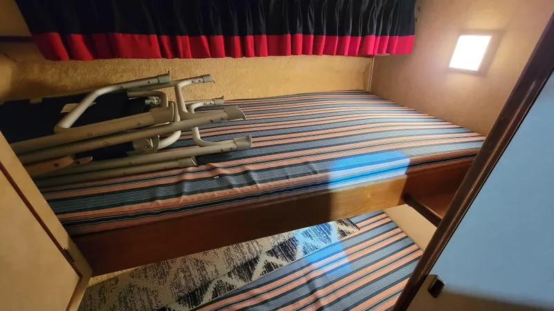 Slide: The Image of Interior cabin of a 1983 Bertram 33 Flybridge Cruiser with striped bedding. - 26