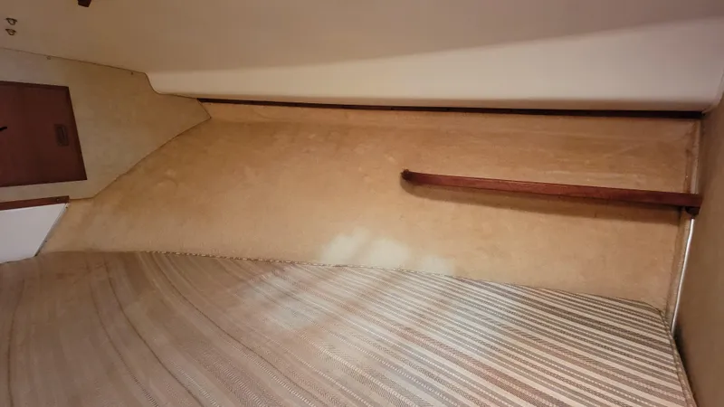 Slide: The Image of Interior cabin of a 1983 Bertram 33 Flybridge Cruiser with beige walls and striped bedding. - 27