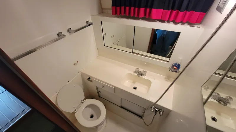 Slide: The Image of 1983 Bertram 33 Flybridge Cruiser bathroom with sink, toilet, and mirror. - 29
