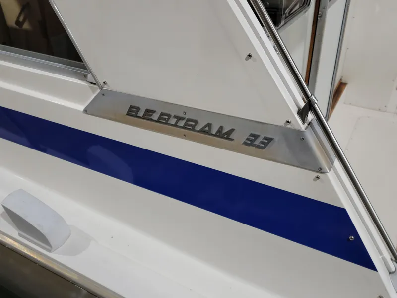 Slide: The Image of 1983 Bertram 33 Flybridge Cruiser with blue stripe and nameplate detail. - 4
