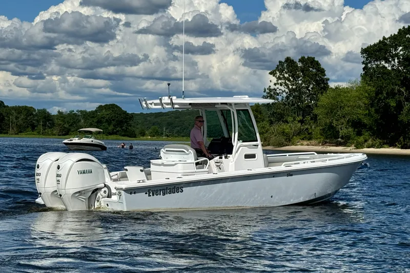 Slide: The Image of 2024 Everglades 273 Center Console boat cruising on a lake with scenic background. - 2