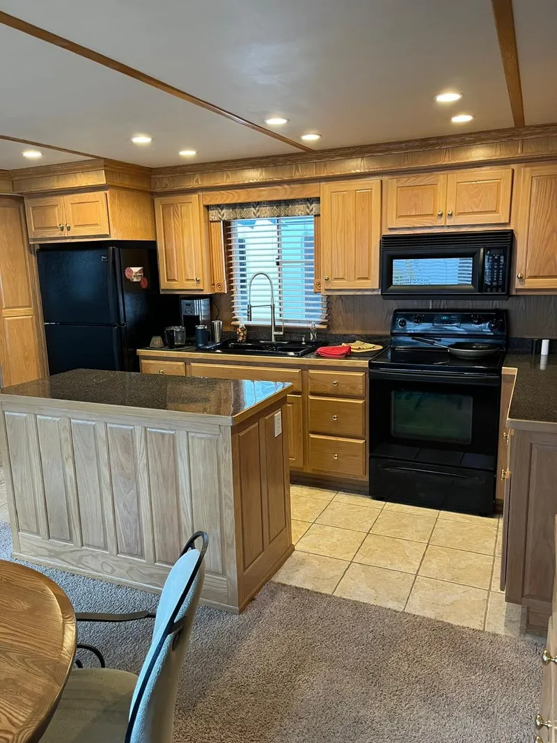 Slide: The Image of Modern kitchen in a 2003 Lakeview houseboat with wooden cabinets and black appliances. - 12