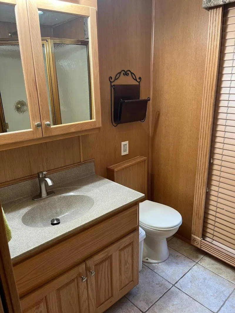 Slide: The Image of 2003 Lakeview Houseboat bathroom with wooden cabinets and tiled floor. - 21