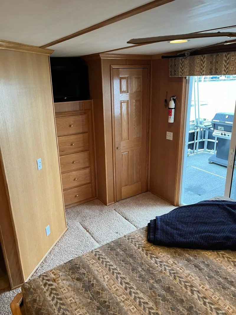 Slide: The Image of Interior of a 2003 Lakeview Houseboat bedroom with wood paneling and outdoor access. - 23