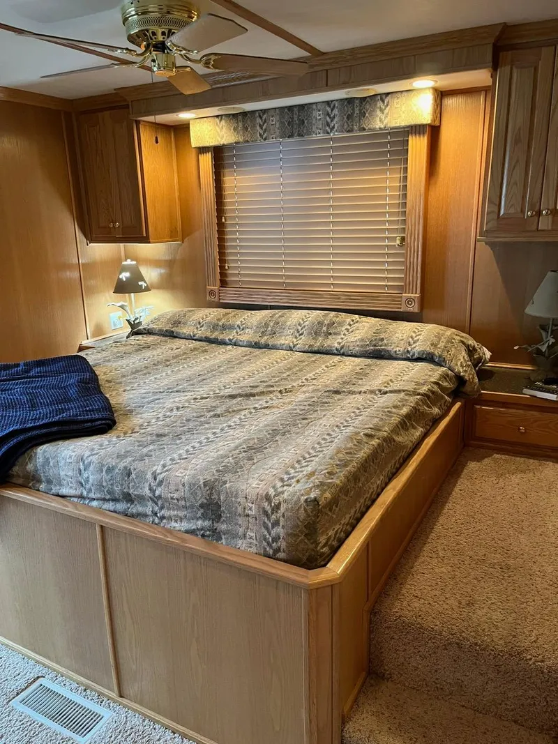 Slide: The Image of 2003 Lakeview Houseboat bedroom with cozy bed, wooden cabinets, and window blinds. - 24