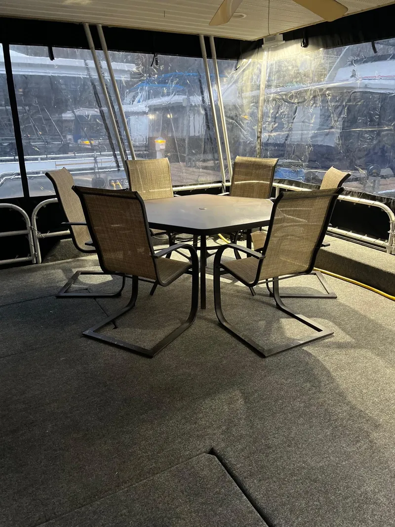 Slide: The Image of 2003 Lakeview Houseboat interior with dining table and chairs on carpeted deck. - 6