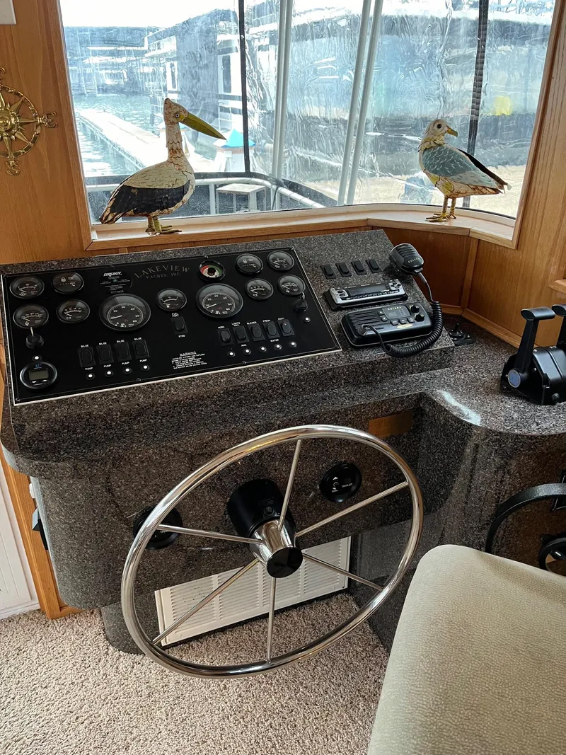 Slide: The Image of 2003 Lakeview Houseboat helm with steering wheel and control panel. - 7