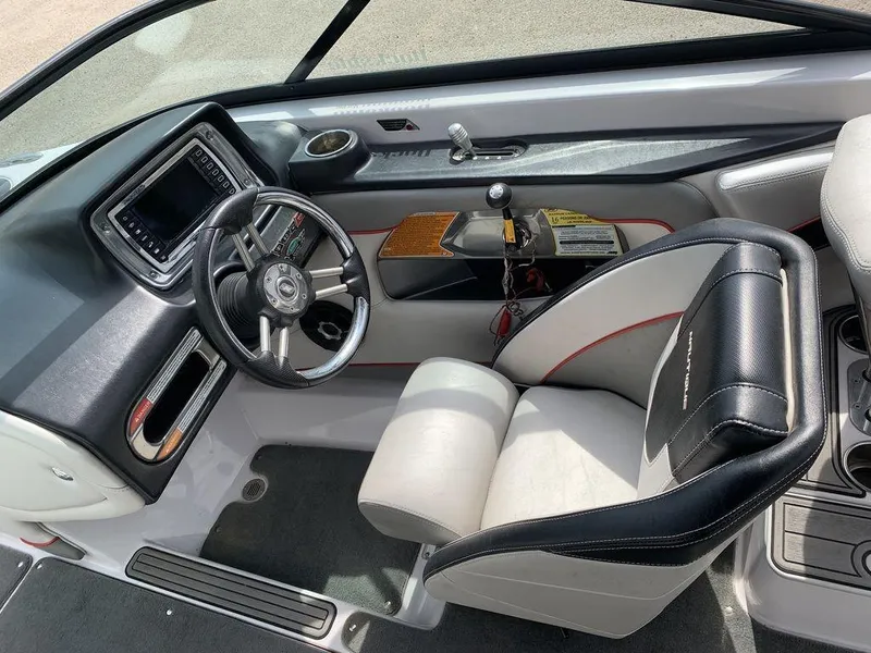 Slide: The Image of 2012 Nautique 230 boat interior, featuring steering wheel, dashboard, and captain's chair. - 4