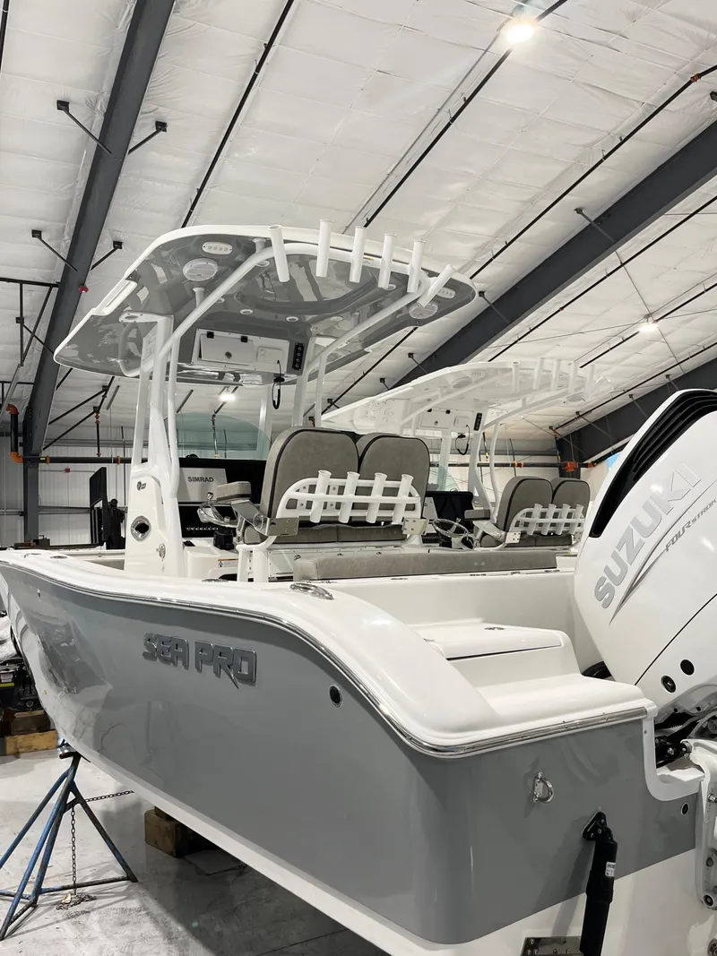 The Image of 2024 Sea Pro 242 DLX boat in a warehouse, featuring a Suzuki outboard motor. - 0