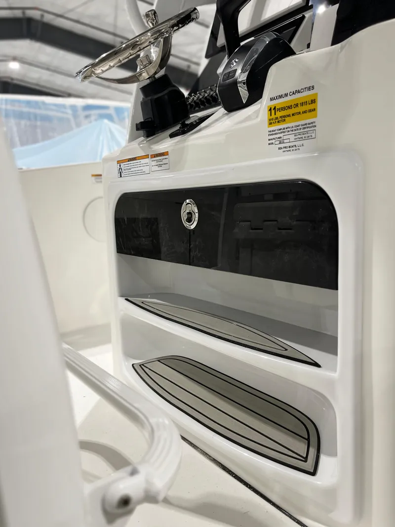 Slide: The Image of 2024 Sea Pro 242 DLX boat console with storage compartments and steering wheel. - 7