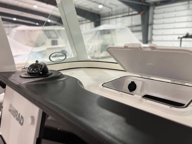 Slide: The Image of 2024 Sea Pro 242 DLX boat dashboard with compass and storage compartment. - 7