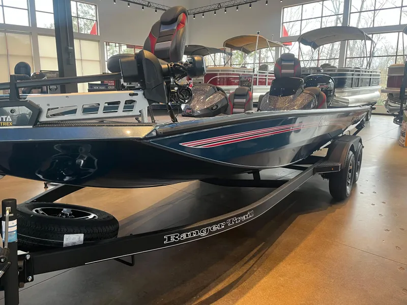 Slide: The Image of 2024 Ranger RT198P fishing boat in showroom, featuring dual axles and modern seating. - 2