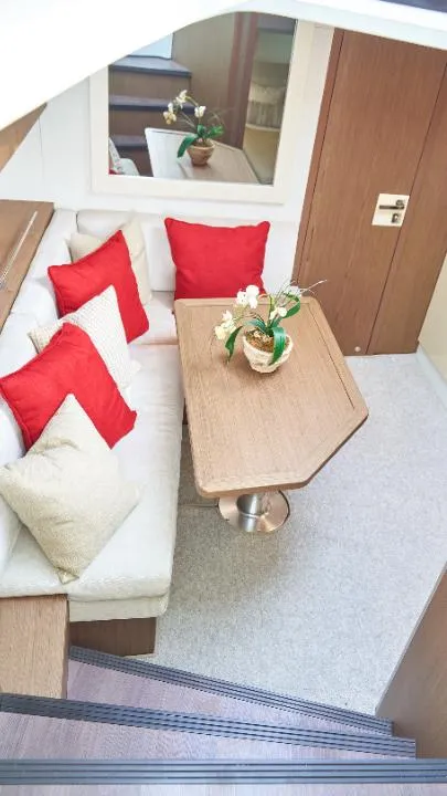 Slide: The Image of Interior of 2018 Beneteau 40 Gran Tourismo with cozy seating and red cushions. - 2