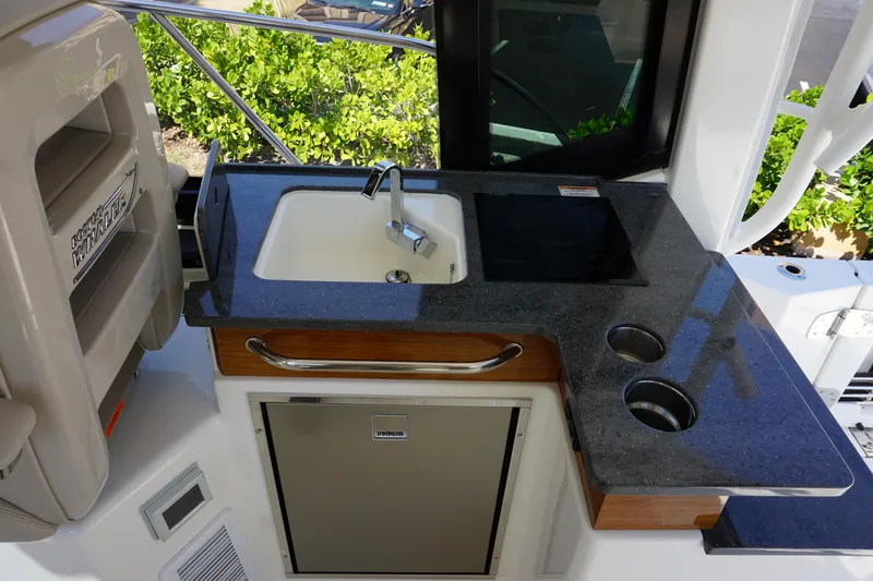 Slide: The Image of 2025 Boston Whaler 365 Conquest boat kitchenette with sink, stove, and storage. - 38