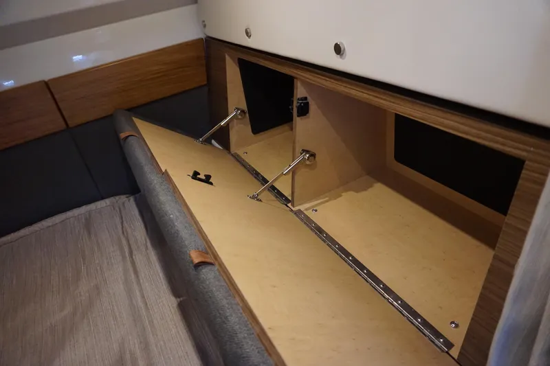 Slide: The Image of 2025 Boston Whaler 365 Conquest interior storage compartment with wooden finish and hydraulic hinges. - 58