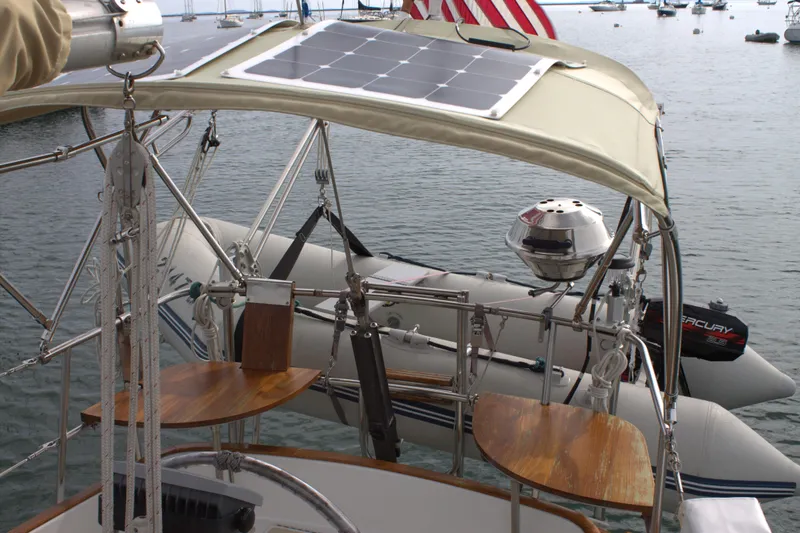 Slide: The Image of 1980 Bristol 35.5 sailboat with solar panel and dinghy on calm water. - 19