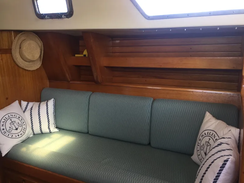 Slide: The Image of Interior of 1980 Bristol 35.5 sailboat with cushioned seating and nautical-themed pillows. - 35