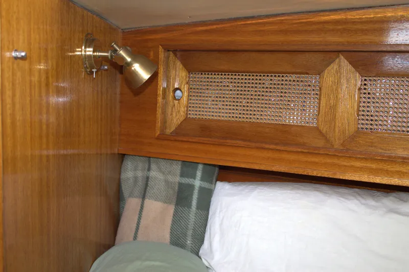 Slide: The Image of 1980 Bristol 35.5 yacht interior, wooden cabinet, reading light, and cozy bedding. - 46