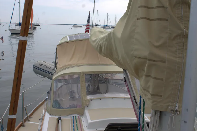 Slide: The Image of 1980 Bristol 35.5 sailboat docked with beige canvas cover, calm waters, and other boats in background. - 7