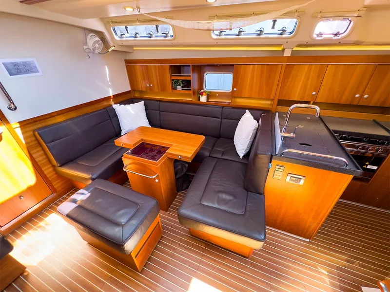 Slide: The Image of 2014 Hanse 445 yacht interior with wooden cabinetry, black seating, and dining area. - 32