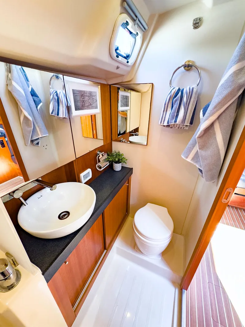 Slide: The Image of 2014 Hanse 445 yacht bathroom with modern sink, toilet, and wooden cabinetry. - 34