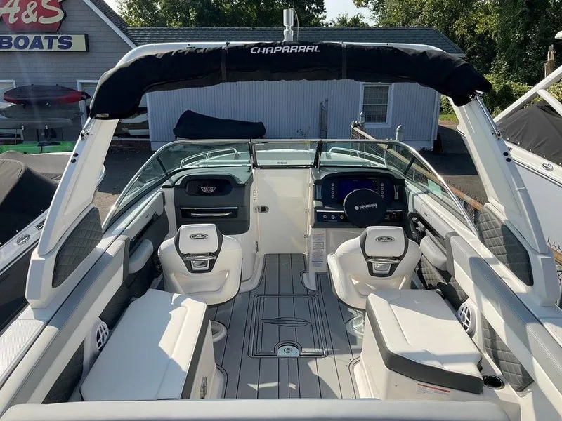 Slide: The Image of 2024 Chaparral 267 SSX boat interior with seating and dashboard, docked at a marina. - 28