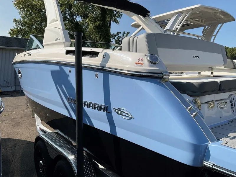 Slide: The Image of 2024 Chaparral 267 SSX boat in light blue and black, parked on a trailer. - 3