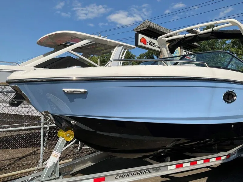 Slide: The Image of 2024 Chaparral 267 SSX boat on trailer, blue and white exterior, sunny day. - 4
