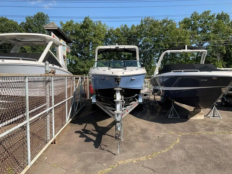 Slide: The Image of 2024 Chaparral 267 SSX boat on trailer, parked between two other boats. - 5