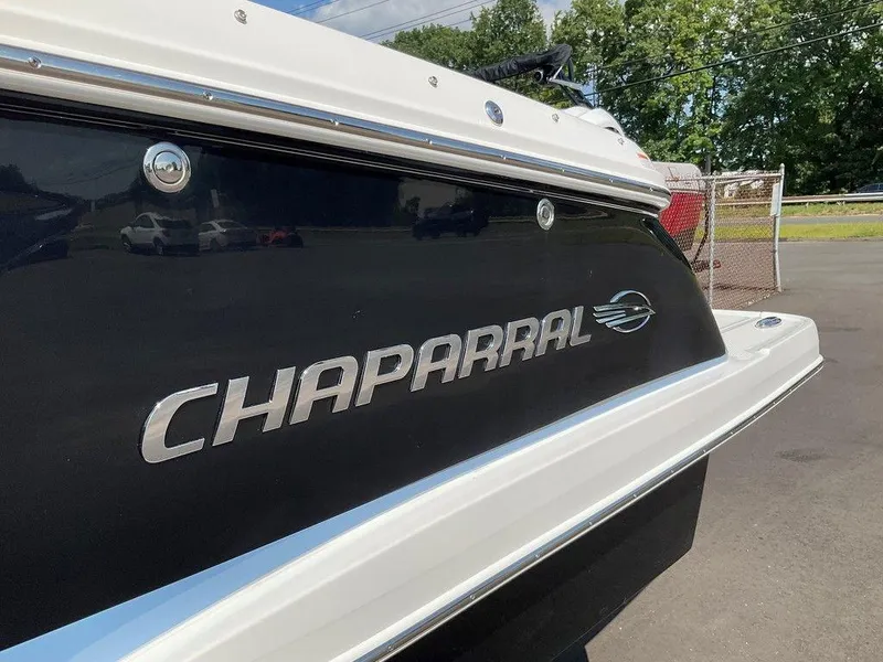 Slide: The Image of 2024 Chaparral 270 OSX boat, rear view with logo, parked outdoors. - 12