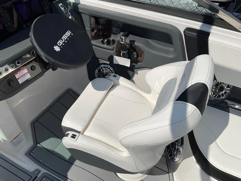 Slide: The Image of 2024 Chaparral 270 OSX boat cockpit with white captain's chair and steering wheel. - 15