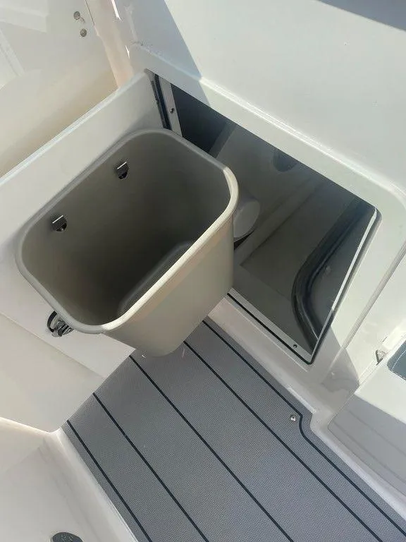 Slide: The Image of 2024 Chaparral 270 OSX boat interior with storage compartment and trash bin. - 19