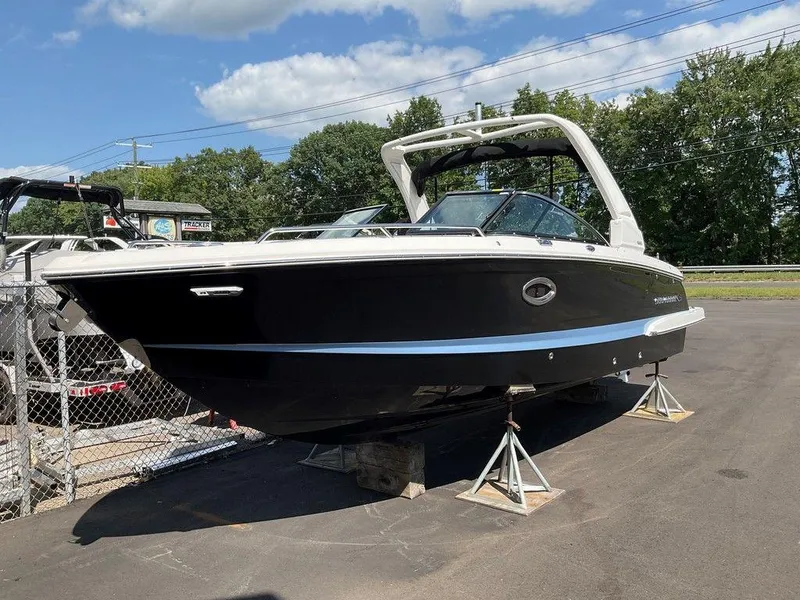Slide: The Image of 2024 Chaparral 270 OSX boat on display, black hull, outdoor setting. - 2