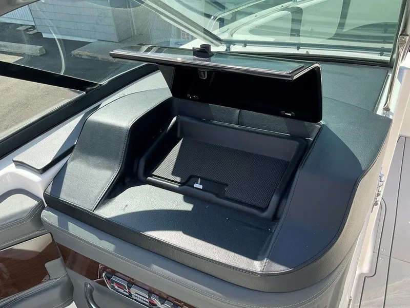 Slide: The Image of 2024 Chaparral 270 OSX boat dashboard with open storage compartment. - 34