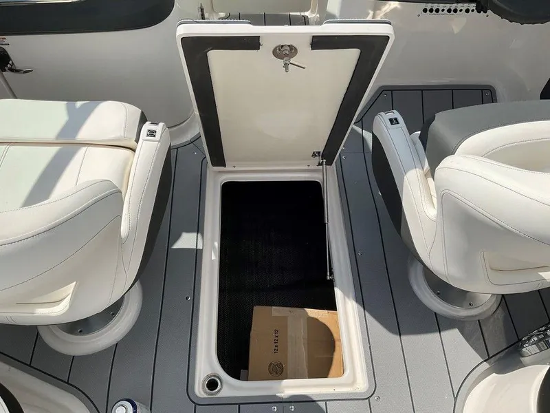 Slide: The Image of 2024 Chaparral 270 OSX boat interior with open storage compartment between seats. - 9
