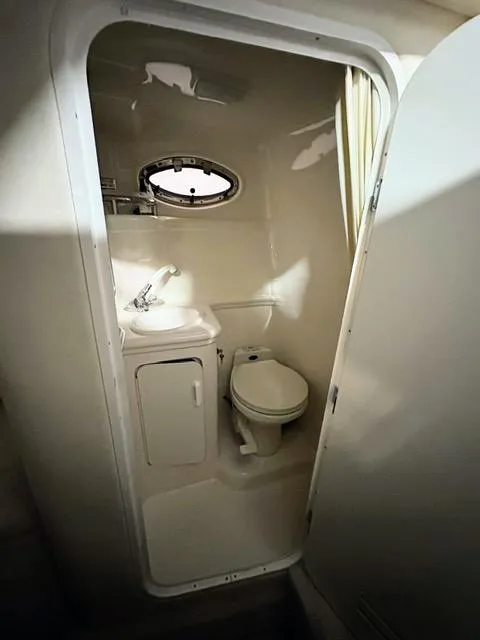 Slide: The Image of Compact bathroom in 2001 Sea Ray 260 Sundancer boat with sink, toilet, and porthole window. - 9