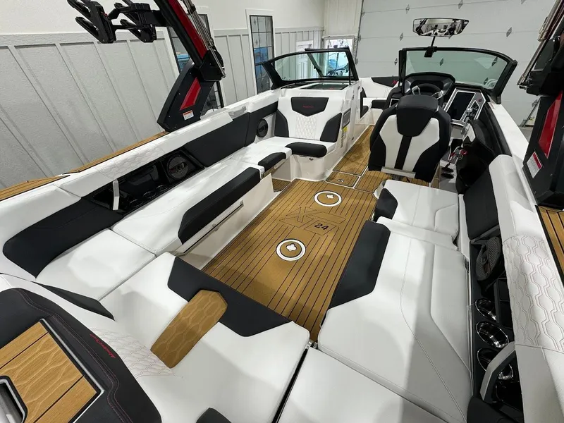 Slide: The Image of 2024 MasterCraft XT24 boat interior with white and black seating, wood flooring, and modern dashboard. - 15