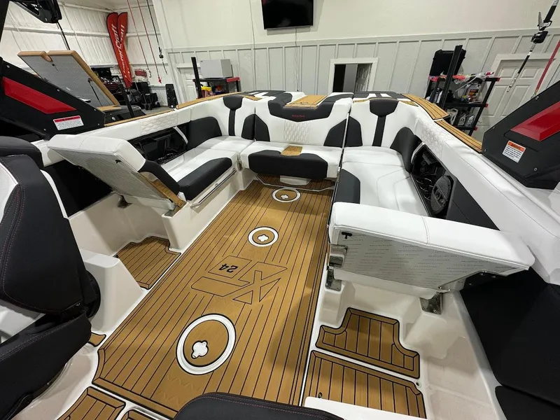 Slide: The Image of 2024 MasterCraft XT24 boat interior with teak flooring and white cushioned seating. - 17