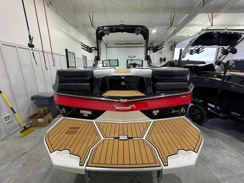 Slide: The Image of 2024 MasterCraft XT24 boat in a showroom, rear view with teak swim platform. - 8