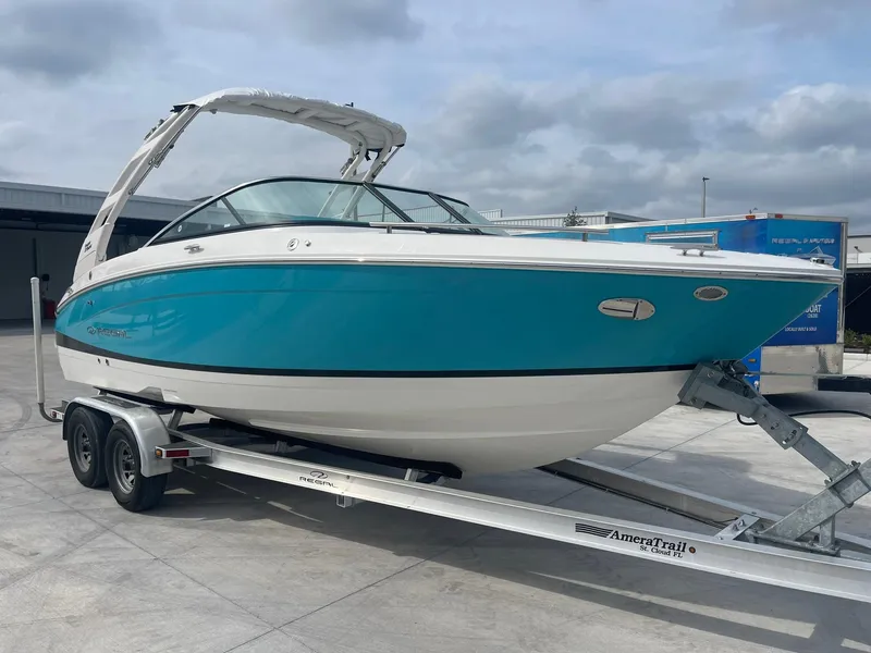 Slide: The Image of 2024 Regal LS4 boat on trailer, blue and white exterior, docked outdoors. - 0
