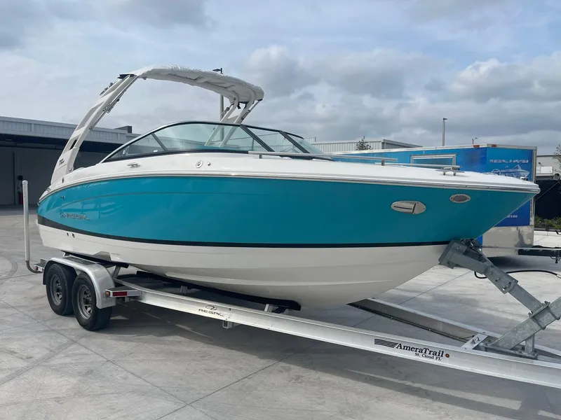 Slide: The Image of 2024 Regal LS4 boat on trailer, blue and white exterior, docked outdoors. - 2