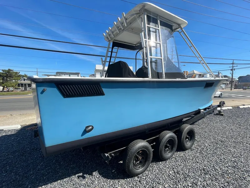 Slide: The Image of 1968 Wahoo Alglas 25 boat on a triple-axle trailer, blue hull, and white cabin. - 13