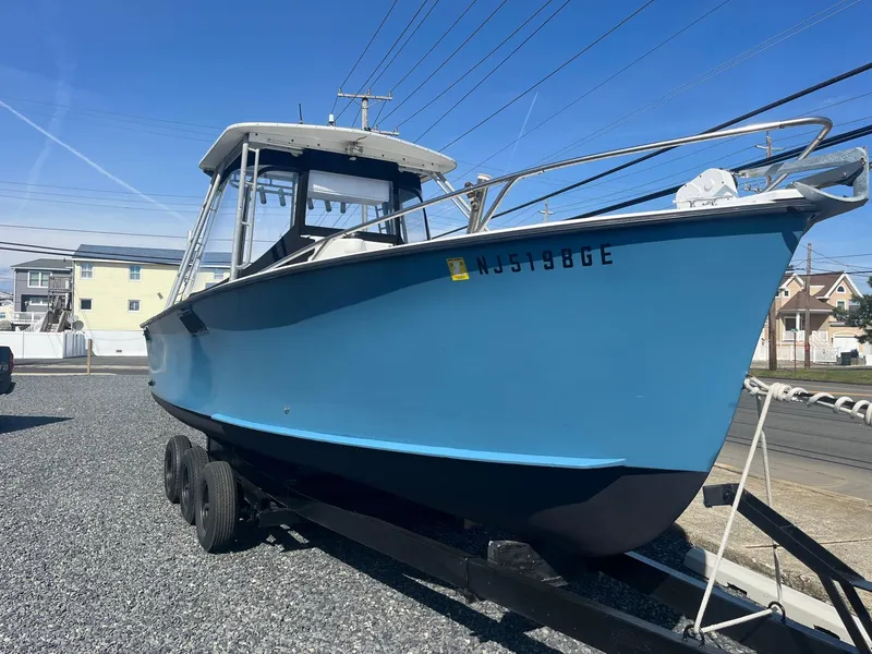 Slide: The Image of 1968 Wahoo Alglas 25 boat on trailer, blue hull, parked on gravel lot. - 4