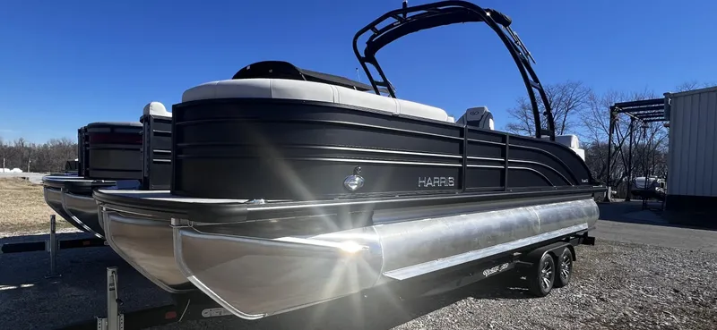 Slide: The Image of 2024 Harris Sunliner 250 Sport pontoon boat on a trailer under a clear blue sky. - 2