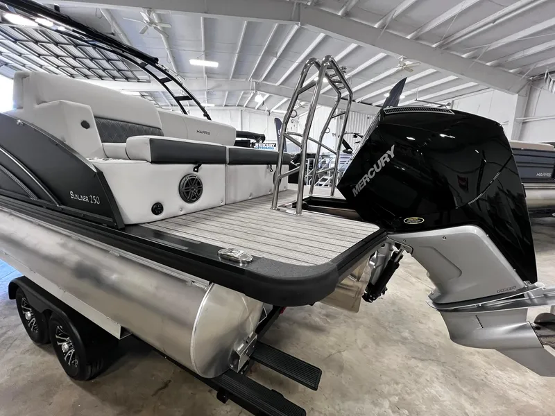 Slide: The Image of 2024 Harris Sunliner 250 Sport pontoon boat with Mercury outboard motor in showroom. - 25